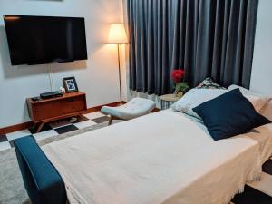 a bedroom with a bed and a flat screen tv at Entire 2-storey house, 2 br, 2 toilet and shower, 2 car parks, only 400 m from MRT Huai Kwang in Ban Na Song