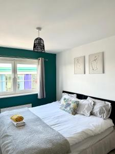 a bedroom with a white bed with a green wall at Cosy 2 Bed Apartment 5 min walk from London Tube Station in Barkingside