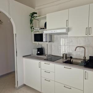 eine Küche mit weißen Schränken und einem Waschbecken in der Unterkunft Cinzia's House of Mirrors in Pisa