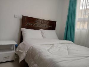 1 cama con cabecero de madera y cortina verde en Luxurious Homes AthiRiver, en Athi River