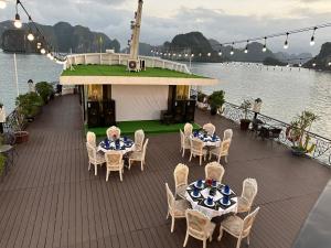 una terrazza con tavoli e sedie su una nave da crociera di Halong AQUAR CRUISE a Ha Long