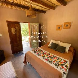 a bedroom with a bed with a floral blanket on it at KUSY WAYRA in Maimará