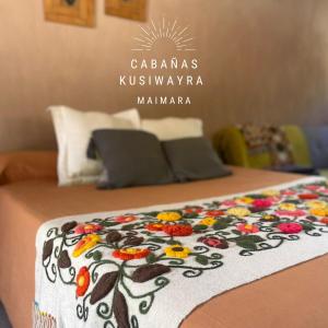 - un lit avec une couverture fleurie dans l'établissement KUSY WAYRA, à Maimará