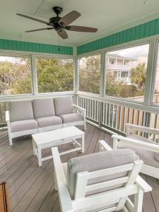 a screened in porch with white furniture and windows at The Gentleman Pirate in Edisto Island