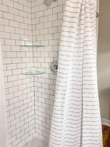 a shower curtain in a white tiled bathroom at The Gentleman Pirate in Edisto Island