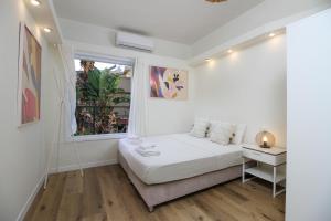 a white bedroom with a bed and a window at Rosen Villa at Ramat Hahayal in Tel Aviv