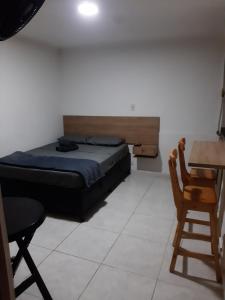 a bedroom with a bed and a table and a chair at Mundo Turismo Hostel in Medellín