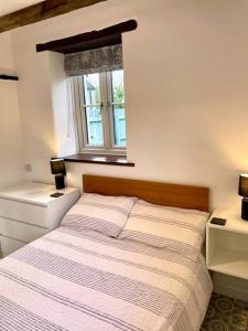 a bedroom with a bed with a window and two night stands at The Cowshed - Cottage in Cornwall in Jacobstow