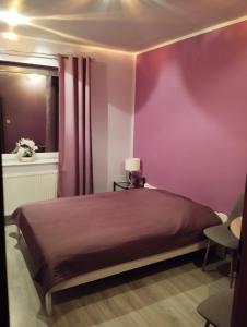 シュチェチンにあるWidokowa Apartamentの紫の壁のベッドルーム1室(ベッド1台付)