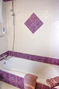 y baño con bañera y azulejos morados. en Chambres d'Hôtes Carpe Diem, en Callian