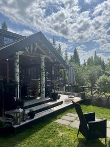 a house with a patio with a chair and an umbrella at Koselig rom i tømmerhus, inkl morgenkaffe in Eidsvoll