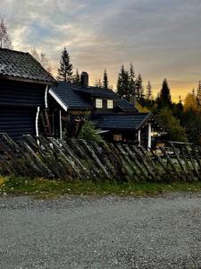 a house with a wooden fence in front of it at Koselig rom i tømmerhus, inkl morgenkaffe in Eidsvoll