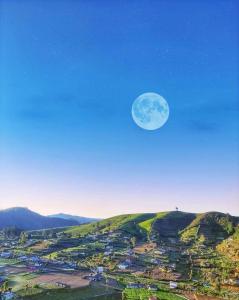 Una luna llena elevándose sobre una ciudad en una colina en Cabin 7000 feet Nuwaraeliya, en Nuwara Eliya