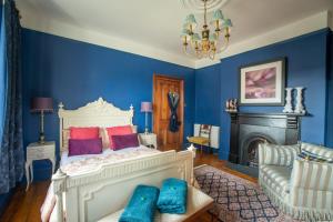 a bedroom with blue walls and a bed with purple pillows at House of Brohedyn in Newcastle Emlyn