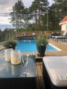 um copo de vinho numa mesa ao lado de uma piscina em Leilighet i Sørlandshus i Son - Sjøutsikt - Nær Son Spa em Son