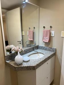 a bathroom with a sink and a vase with flowers at American Flat in São Luís