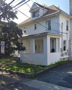 una casa blanca con un perro sentado en la ventana en NYC Gateway: Cozy Home with Easy Access, en Passaic