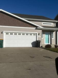una casa con una puerta de garaje blanca y un camino de entrada en Charming Retreat with Modern Comforts en West Fargo