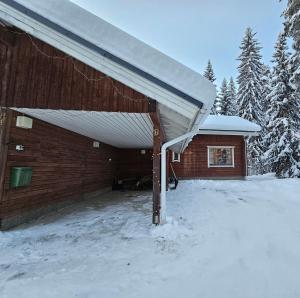 a building with a snow covered roof in the snow at Tahko Villa Vaarna in Tahkovuori