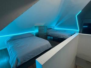 two beds in a room with a blue lighting at NYC Gateway: Cozy Home with Easy Access in Passaic