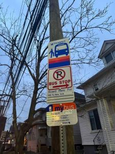 una señal de parada de autobús en un poste con señales en él en NYC Gateway: Cozy Home with Easy Access, en Passaic