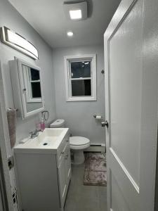 La salle de bains blanche est pourvue de toilettes et d'un lavabo. dans l'établissement NYC Gateway: Cozy Home with Easy Access, à Passaic
