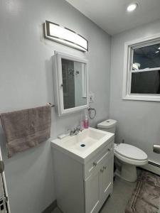 Baño blanco con lavabo y aseo en NYC Gateway: Cozy Home with Easy Access, en Passaic