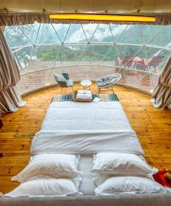 a large bed in a room with a large window at LUXEGLAMP ECOSTAYS in Kūkkāl