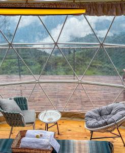 KūkkālにあるLUXEGLAMP ECOSTAYSの椅子と大きなガラス窓が備わる客室です。