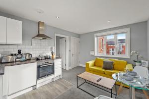 eine Küche und ein Wohnzimmer mit einem gelben Sofa in der Unterkunft BridgeCity Modern Holiday Condo in Maidstone - f8 in Kent