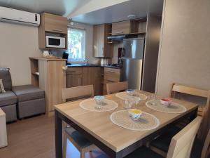 een keuken met een houten tafel met twee borden erop bij Mobil-home climatisé 6 pers en Ardèche in Orgnac-lʼAven