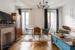 a living room with a fireplace and a table and chairs at Au marche aux puces de saint ouen in Saint-Ouen