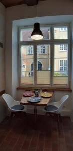 Ferienwohnung Kontor im Traufenhaus في لوبيك: طاولة طعام مع كرسيين ونافذة