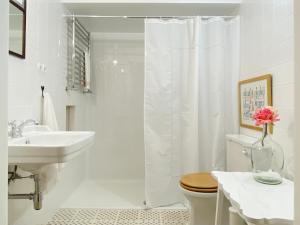 Baño blanco con cortina de ducha y lavamanos en Esquina do Visconde, Guesthouse, en Torre de Moncorvo