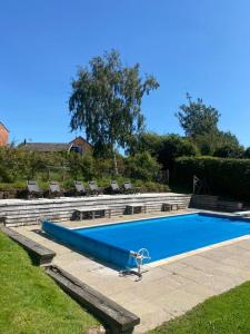 a large swimming pool with chairs and a blue pool at Luxury homely open-plan Barn with log burner & games room in Wrexham