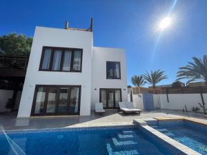 a villa with a swimming pool in front of a house at Villa Blanca Dahab in Dahab