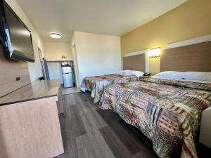 a hotel room with two beds and a flat screen tv at Royal Inn and Suites Charlotte Airport in Charlotte