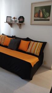 Cama en habitación con almohadas de color naranja y negro en Apartamento aconchegante em Petrópolis en Petrópolis