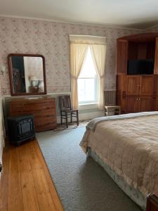 um quarto com uma cama, uma cómoda e um espelho em Antique Mansion B & B em Rutland