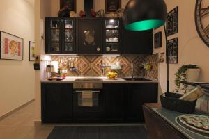Mimma's Ground Floor في روما: مطبخ به دواليب سوداء ومصباح أخضر