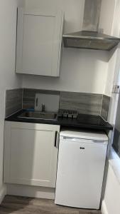 uma pequena cozinha com armários brancos e um lavatório em Gregory Boulevard - Stay Sleep Rest em Nottingham