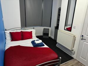 a bed with red pillows and a red blanket at Gregory Boulevard - Stay Sleep Rest in Nottingham