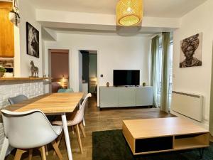 Una sala de estar con una mesa y sillas y un televisor. en Repos entre Paris & Disney, en Nogent-sur-Marne