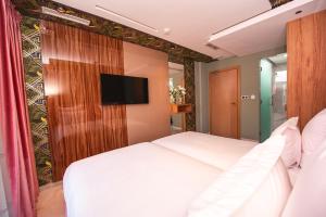 纳祖尔MAGNIFIQUE HOTEL的卧室里有一张白色的床和一台平板电视