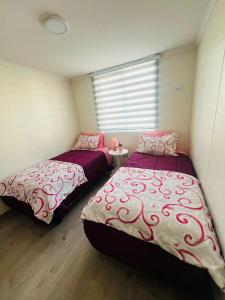 two beds in a room with a window at Hermoso Jardines del Pacifico in La Serena +10 photos