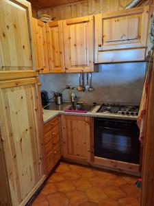 a kitchen with wooden cabinets and a stove top oven at Delizioso appartamento in centro a Champoluc in Champoluc