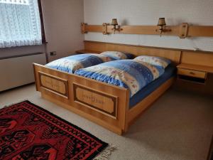 a bedroom with a wooden bed with blue comforter at Ferienhaus Buchen in Schwarzenberg im Bregenzerwald