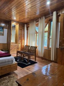 a bedroom with a bed and a bench and windows at Nest Villa Homestay in Nagar