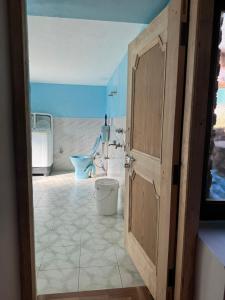 a bathroom with a toilet and a open door at Nest Villa Homestay in Nagar