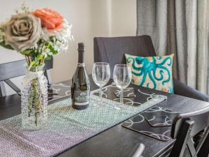 a table with a bottle of wine and two wine glasses at Lovely Magnolia Accommodation 3king Torquay in Torquay